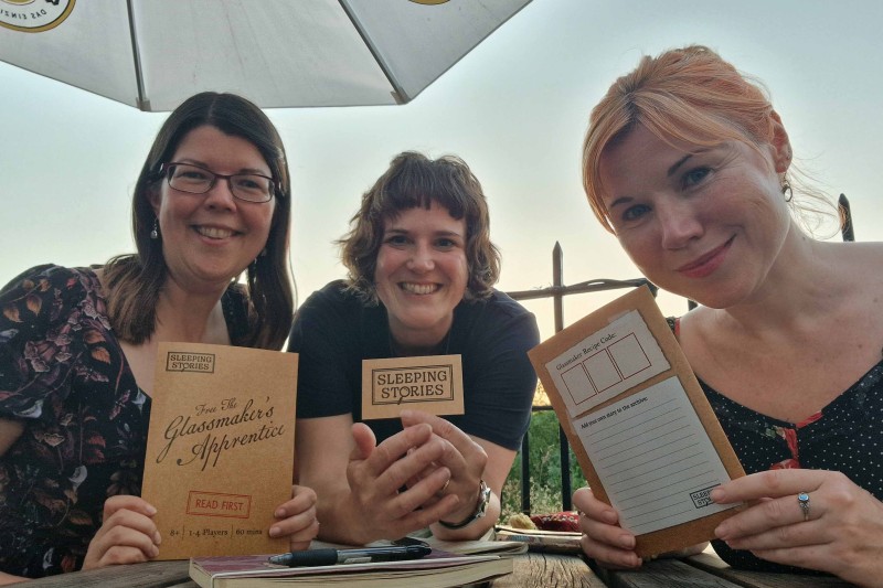 Three ladies holding up some printing scripts to the camera