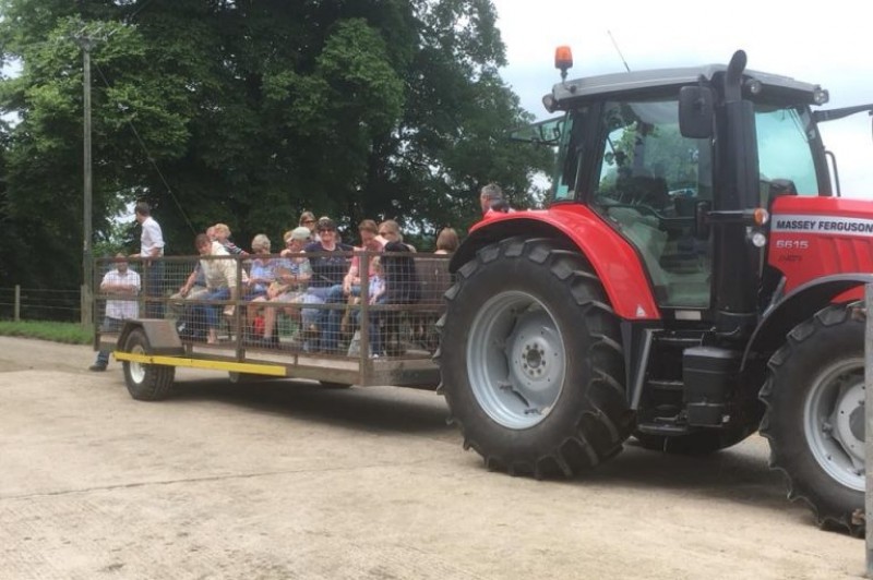 People on a trailer being pulled by a tractor People on a trailer being pulled by a tractor