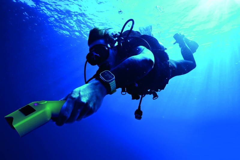 Image of a diver underwater, holding Ocean Insight - a yellow, hand-held device