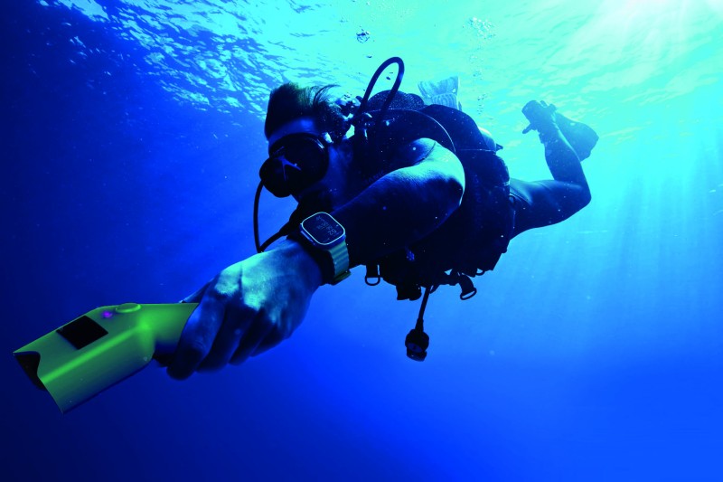 Diver using Ocean Insight Image of a diver underwater, holding Ocean Insight - a yellow, hand-held device