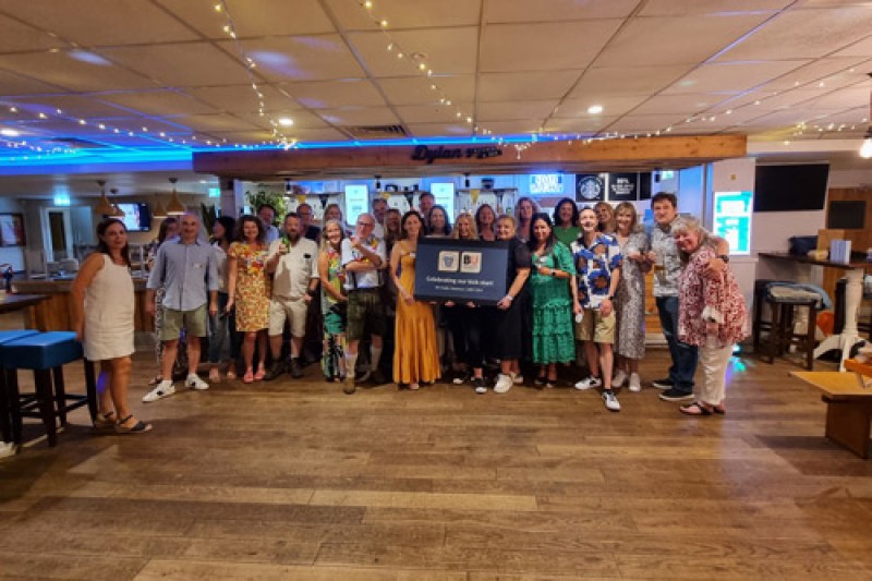 A group of around 30 people standing in Dylans Bar, looking at the camera smiling