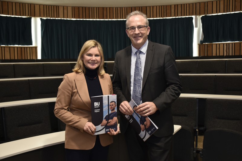 Justine Greening and John Vinney, holding copies of the Impact Report and smiling at the camera