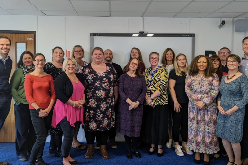 A large group of participants in the programme standing, looking straight at the camera (mostly) smiling