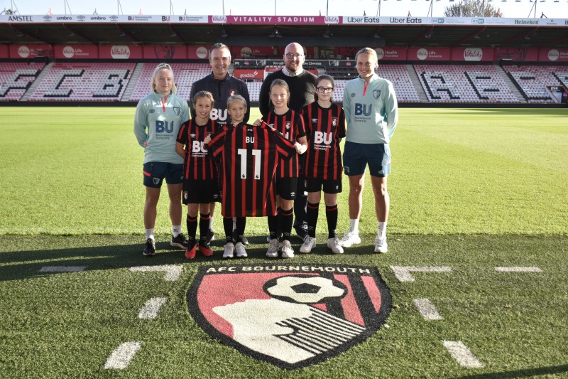 Representatives from BU and AFC Bournemouth holding an official shirt