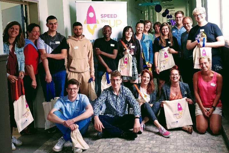 A group of young people in two rows, standing in front of a Speed-You-Up banner