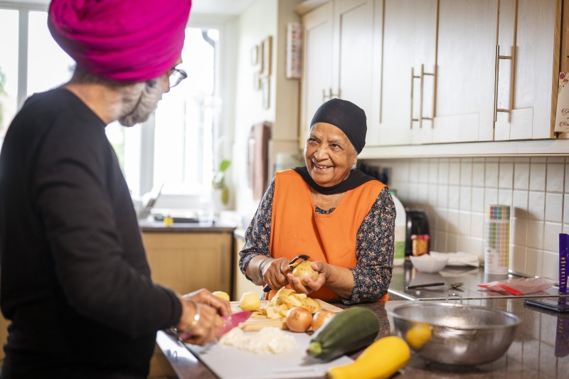 An older Asian couple preparing food in their kitchen 