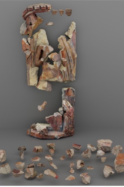 A number of pieces assembled in their original places in the statue and dozens of other pieces scattered in front of it.