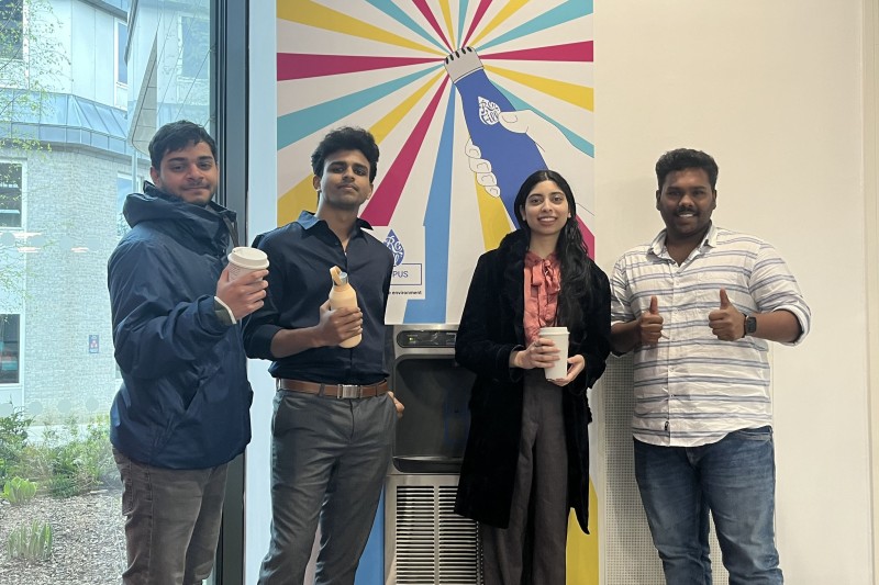 Four students standing in front of a water refill station