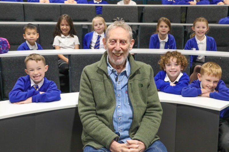 Michael Rosen sitting in front of children from Longfleet C of E Primary School