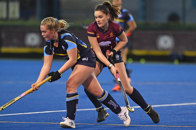Rosie competing in a hockey match, being challenged by an opponent