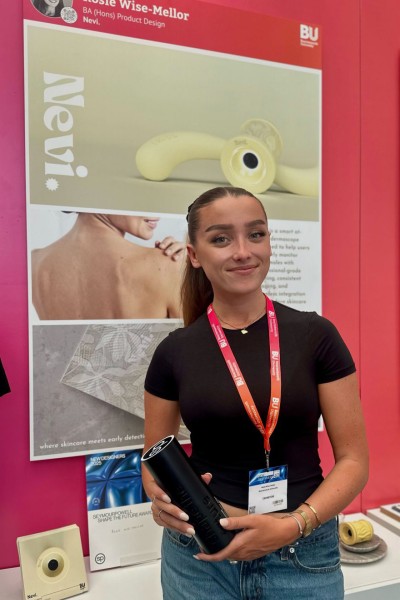 Rosie Wise-Mellor standing in front of a display stand with her product at an exhibition Rosie Wise-Mellor standing in front of a display stand with her product at an exhibition
