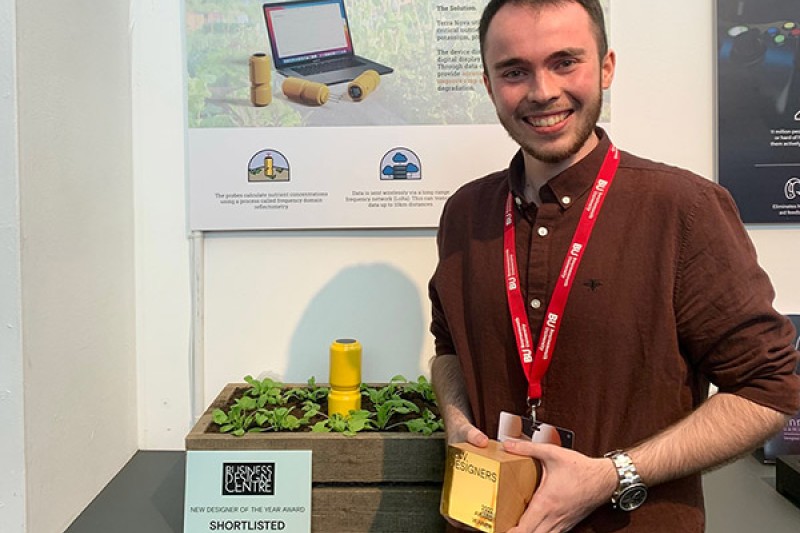 Ryan Waterhouse holds his award next to a prototype of his product design Terra Nova