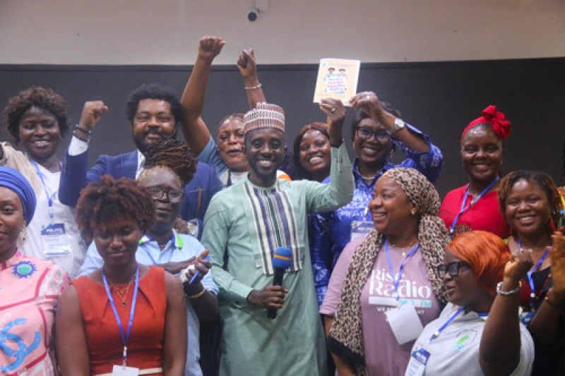 Sierra Leone Government minister holding up the policy document, surrounded by 11 women and 1 man at the launch event 