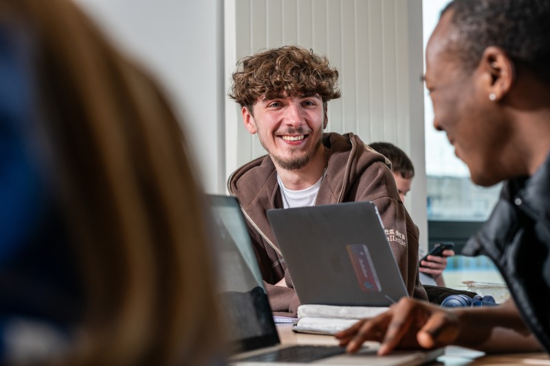 Student looking at another student over a laptop