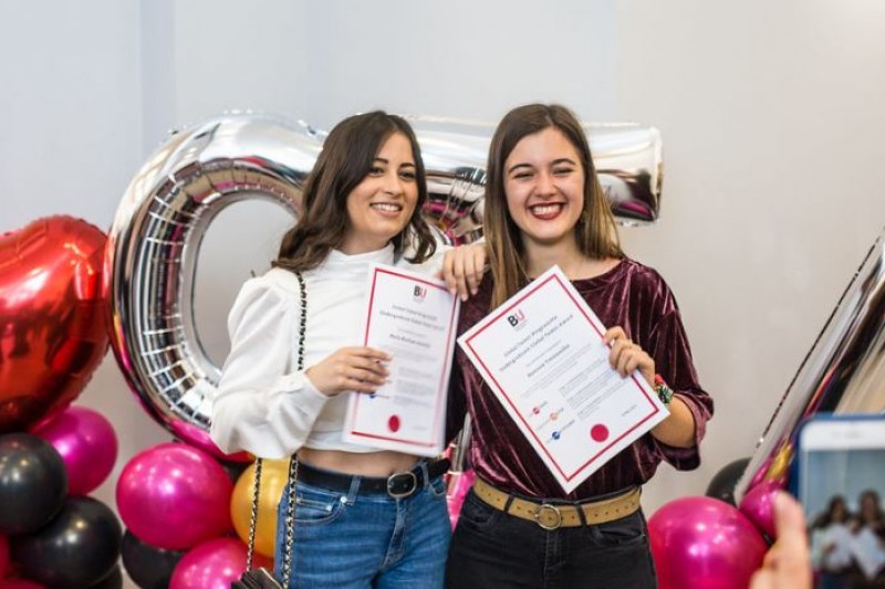 two students holding global talent award certificates