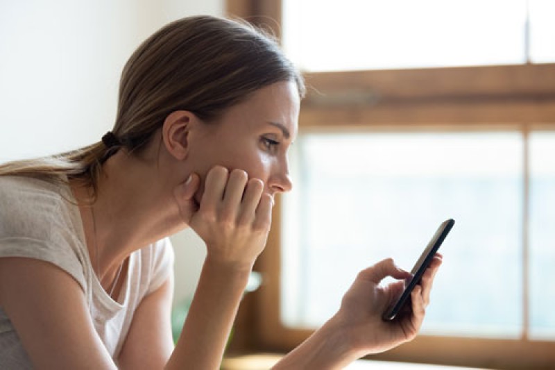 Social media use A young woman looking sad and staring at her mobile phone