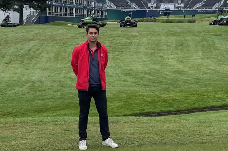 A man standing on a golf course with empty seating behind him