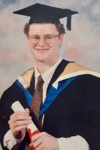 Stephen Reid at his graduation with his cap, gown and scroll