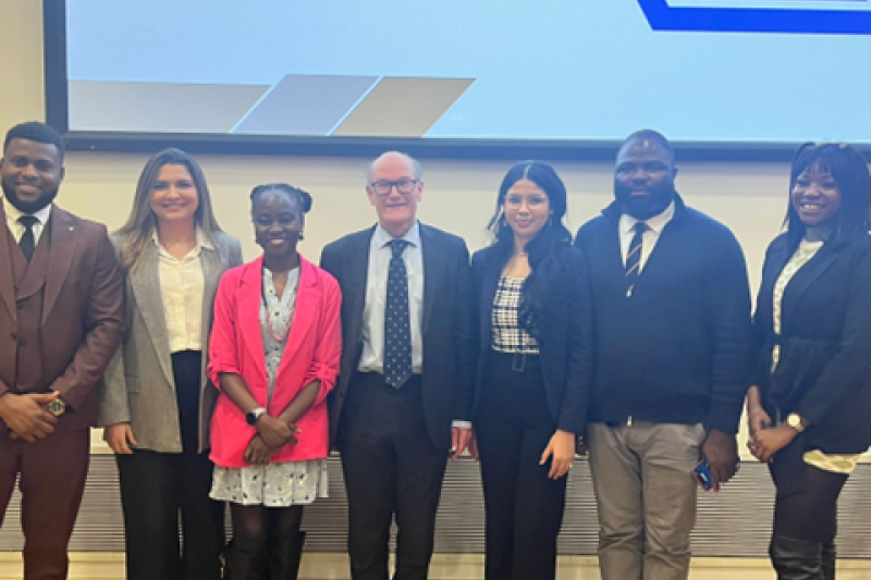 A group of seven speakers looking at the camera, smiling