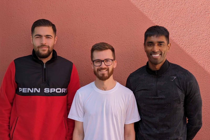 Three men standing in a line, looking at the camera smiling