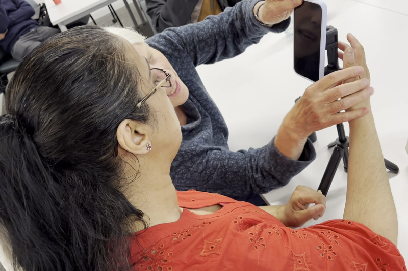 Two people assembling a smartphone onto a mini tripod