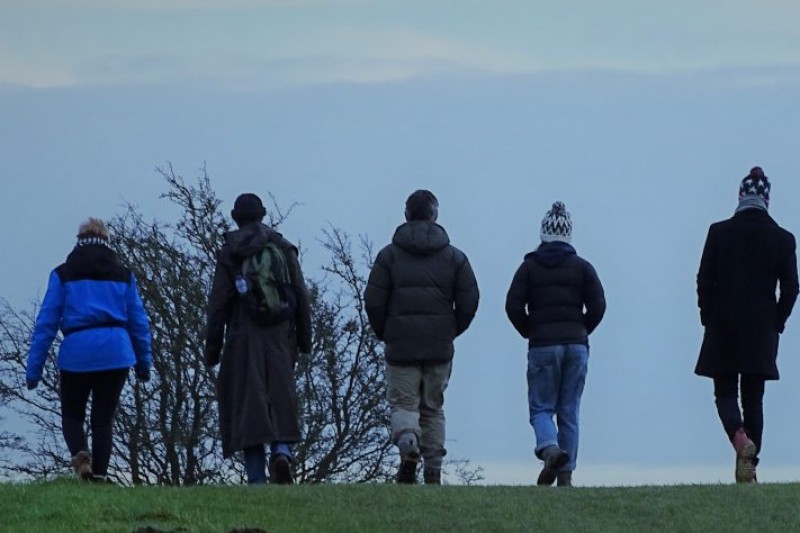 People walking by a large rock