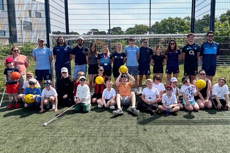 VI children, BU student sport coaches and academics standing in front of a goal at the Sports Day