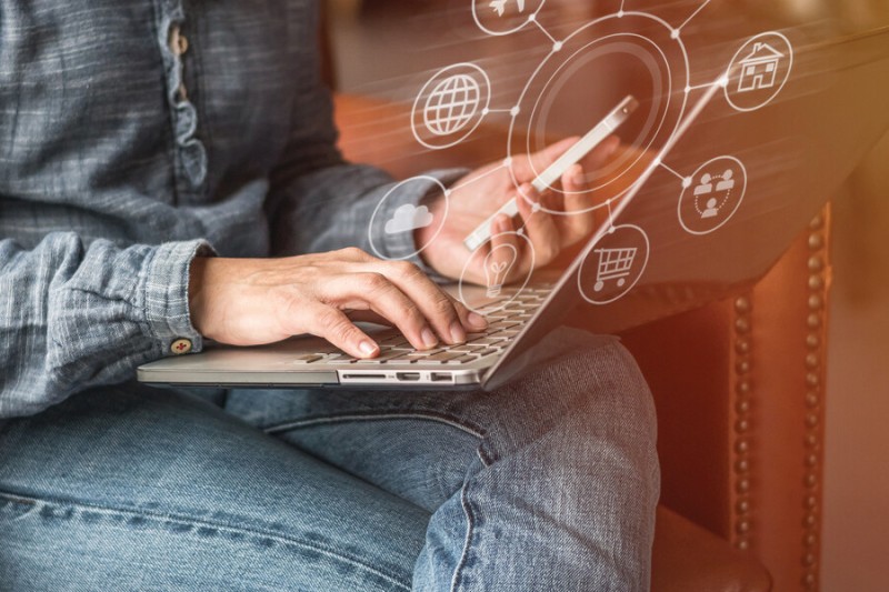 A person sat on a laptop with a phone and icons representing different functions