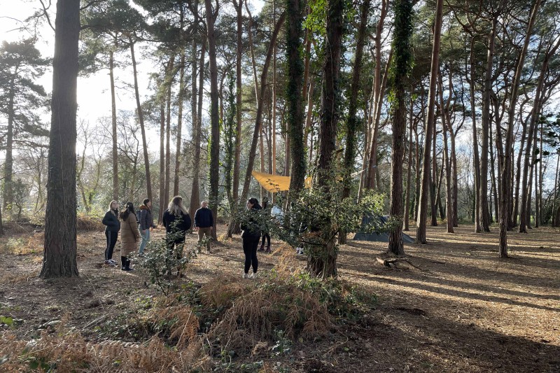 Students standing in a circle in a woodland setting