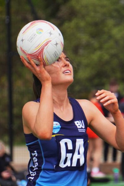 Member of the BU women's netball team aiming the ball at the net Member of the BU women's netball team
