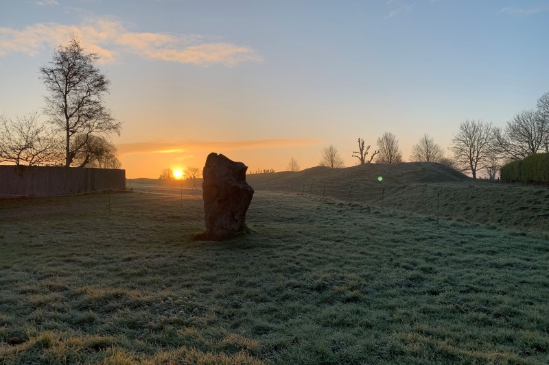 A stone on Avebury Stone circle with the sun rising in the background