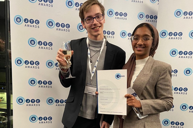 BJTC award A man and a woman holding a certificate, looking at the camera smiling