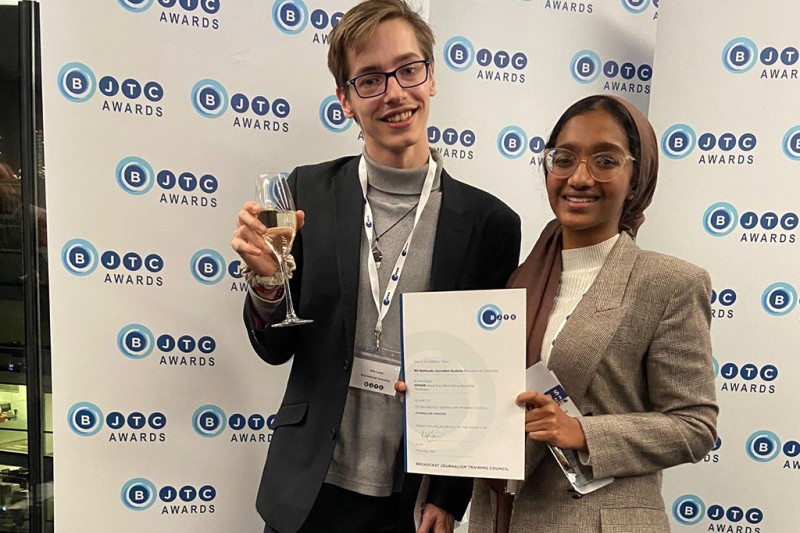 A man and a woman holding a certificate, looking at the camera smiling