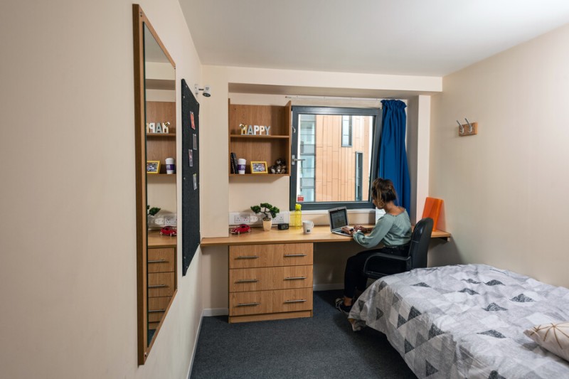 A student studying at their desk in a standard ensuite room in Chesil House