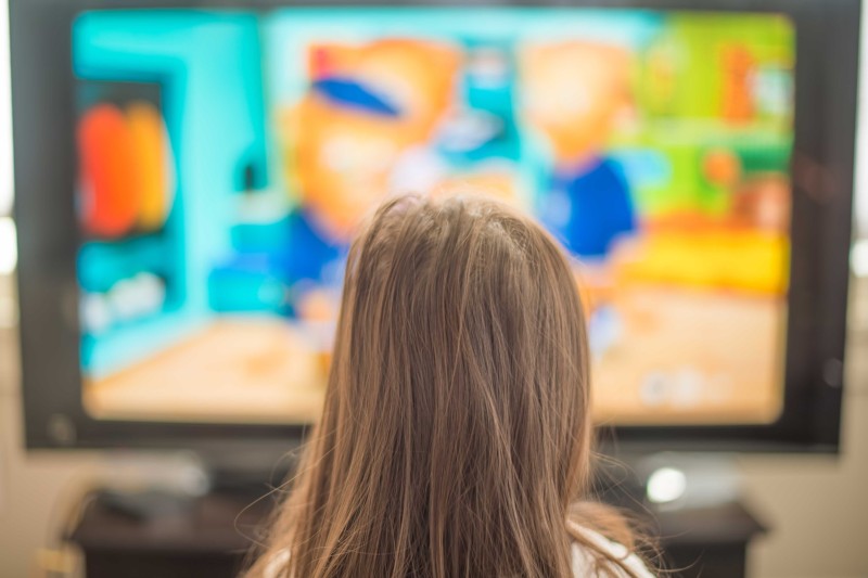 A child sitting in front of a blurred television screen 