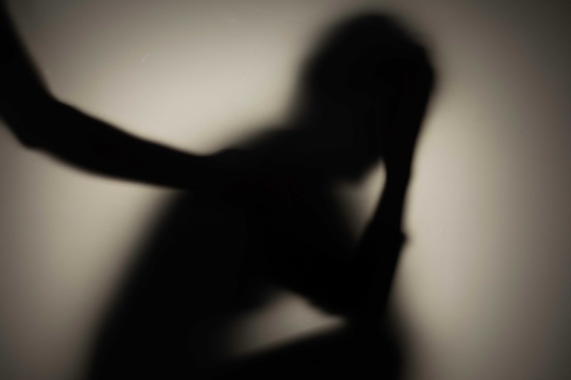 A figure in shadow with their head in their hands A figure in shadow with their head in their hands
