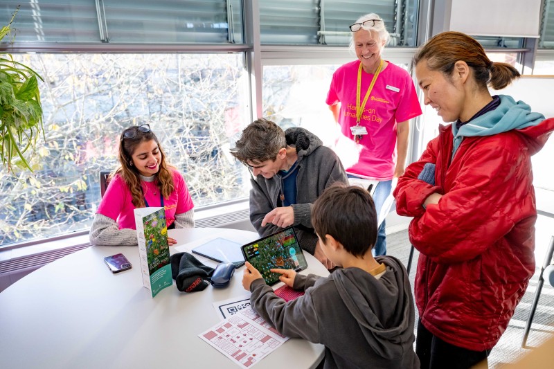 A young boy and an adult looking at iPads with the project team observing