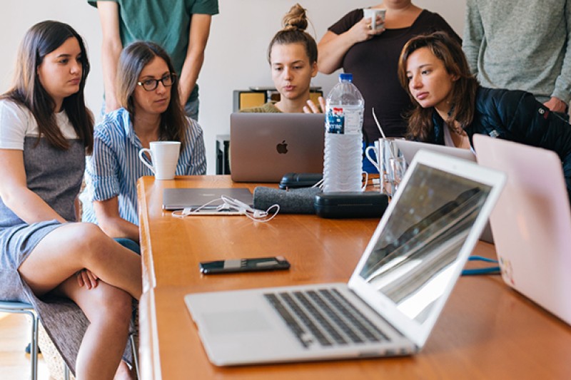 Group of students using laptops at a table Group of students using laptops at a table