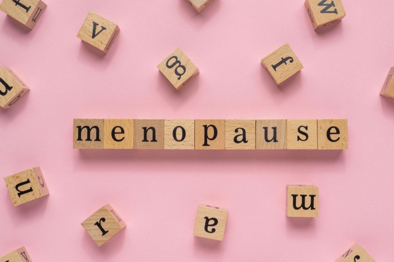 Wooden letters spelling out menopause on a pink background