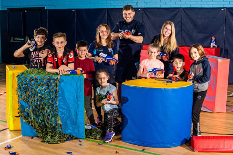 Children at a Nerf war party with SportBU staff