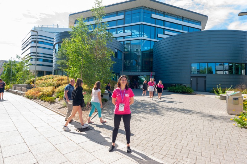 A student ambassador outside the Fusion Building on Talbot Campus, with guests and other ambassadors in the background