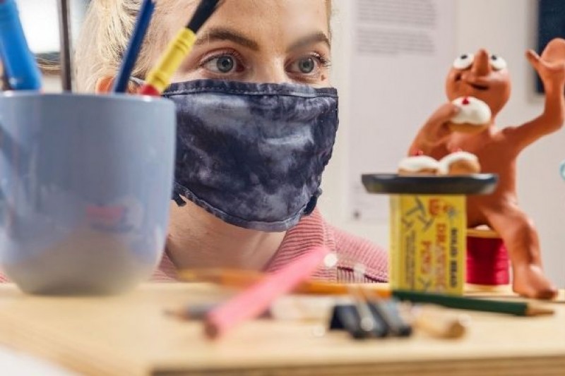 A woman looking at a display featuring a figure or Morph, the animated character