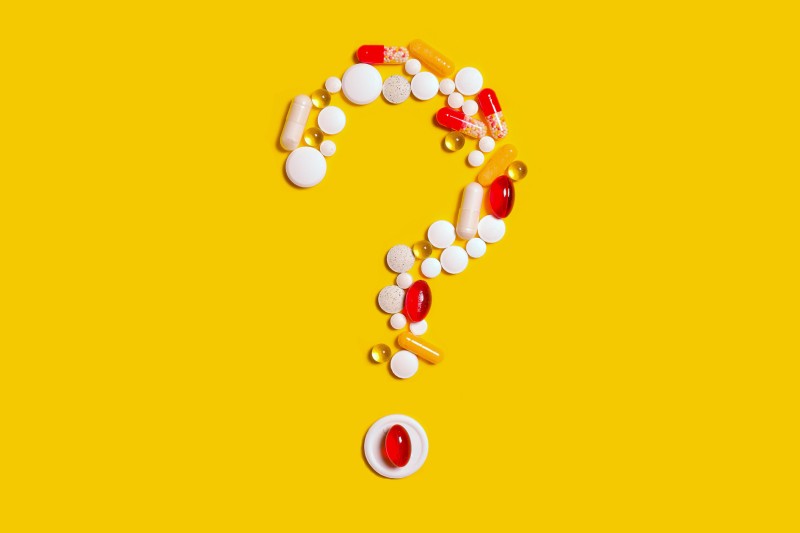 A question mark formed out of pills on a yellow background 
