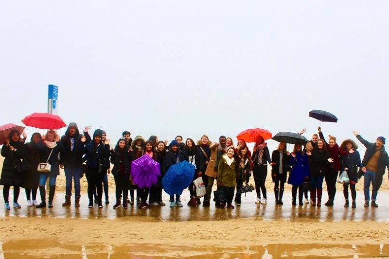 Group of students at the beach holding up umbrellas