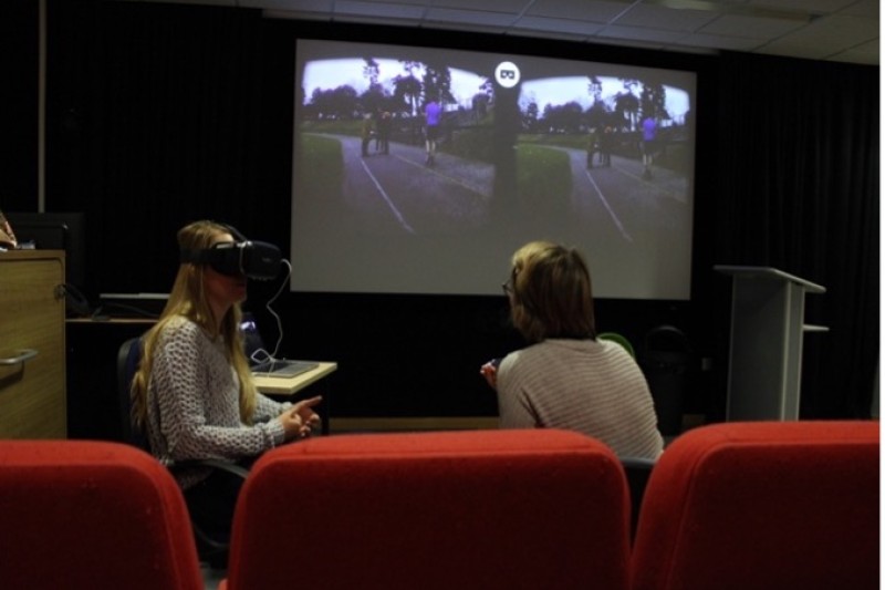 A student wearing VR googles with a screen showing footage behind