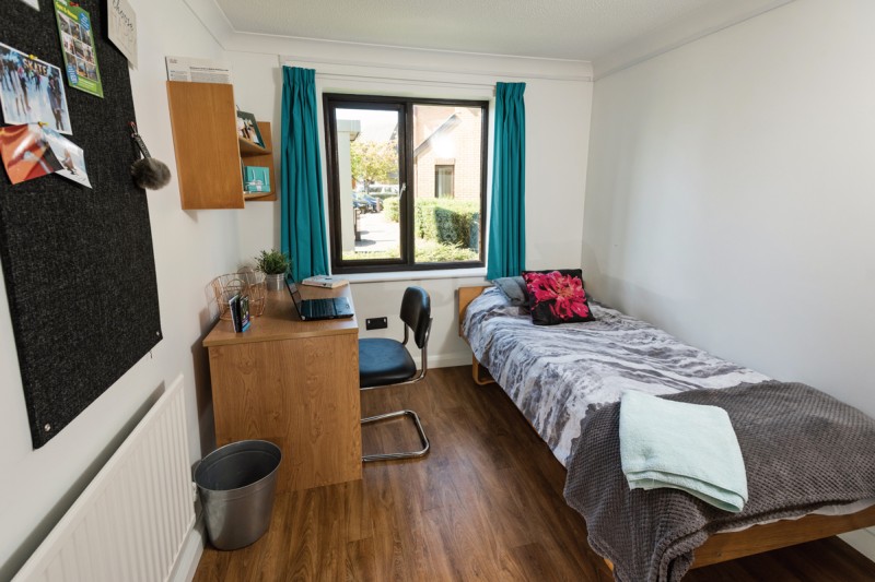 Student Village bedroom on the ground floor with wooden flooring, a desk, chair, and bed