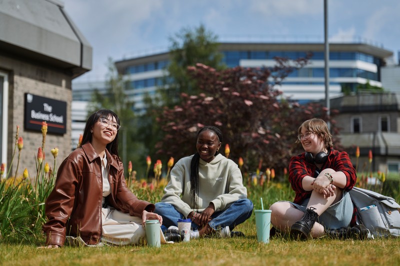 Three students sitting outside on campus